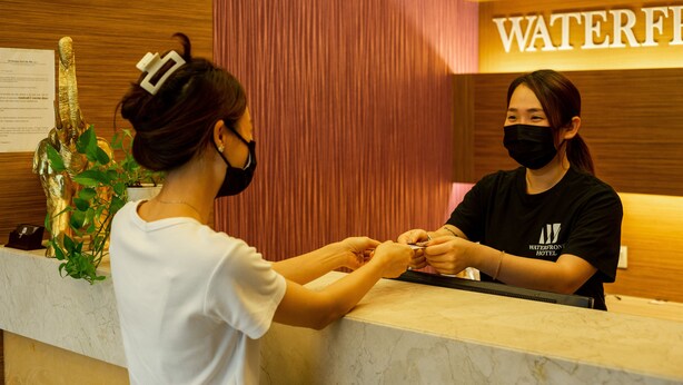 A reception desk at a hotel with a wooden panel wall and a sign that reads "WATERFRONT HOTEL". - WaterFront Boutique Hotel (Port Dickson)