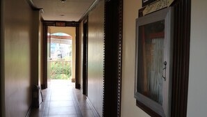 Un pasillo con suelo de baldosas, un cartel de salida de incendios, un cuadro enmarcado y una puerta que da a un espacio exterior.