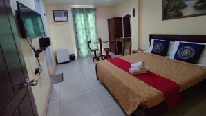 Una habitación de hotel con cama, escritorio, silla, televisión y un cuadro en la pared.