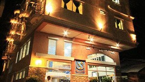 Un edificio de varios pisos con una entrada destacada y un letrero que indica un baño público.