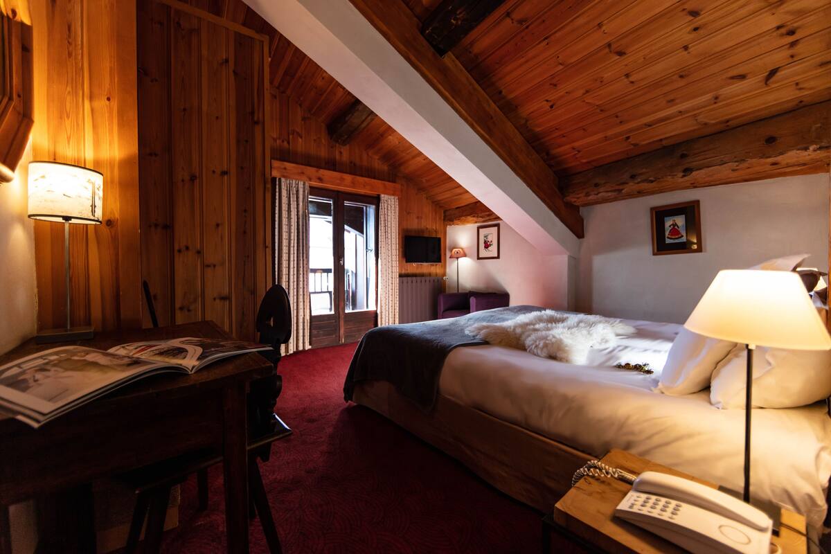 A wooden room with a bed, a desk, and a telephone.