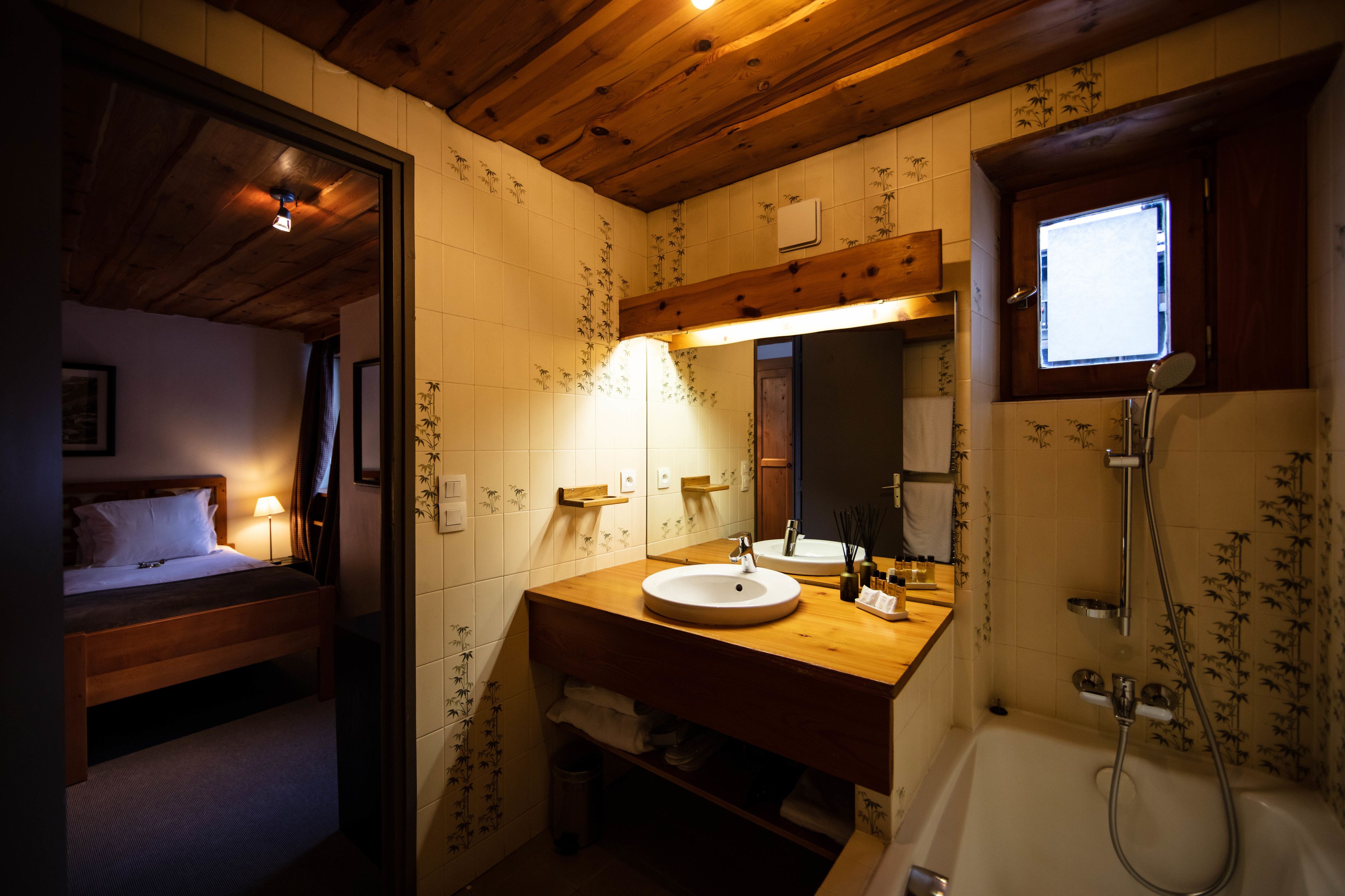 Techo, cama y lavabo de madera, un espejo, una ventana y una ducha.