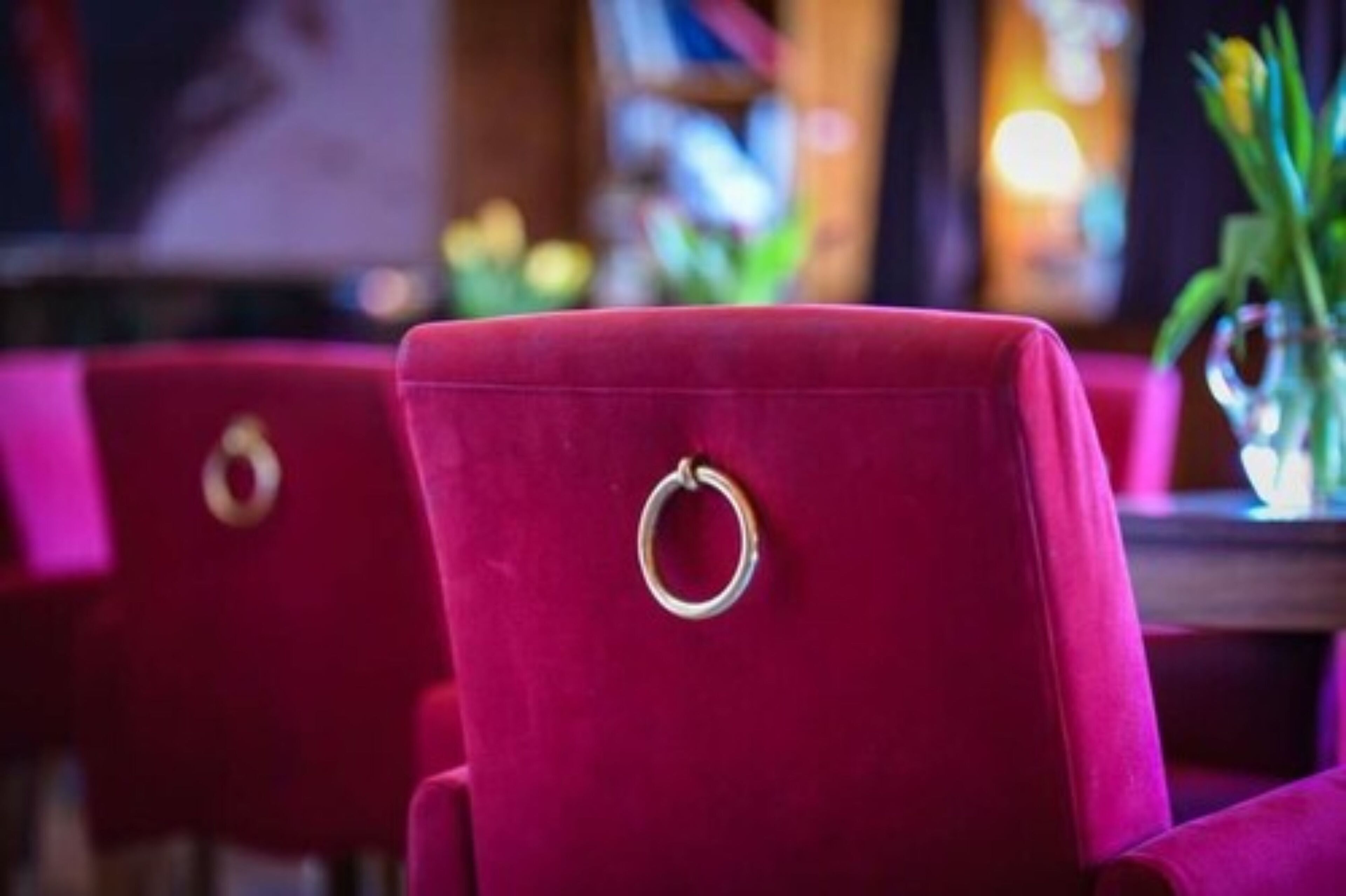 A red upholstered chair with a metal ring on the backrest.