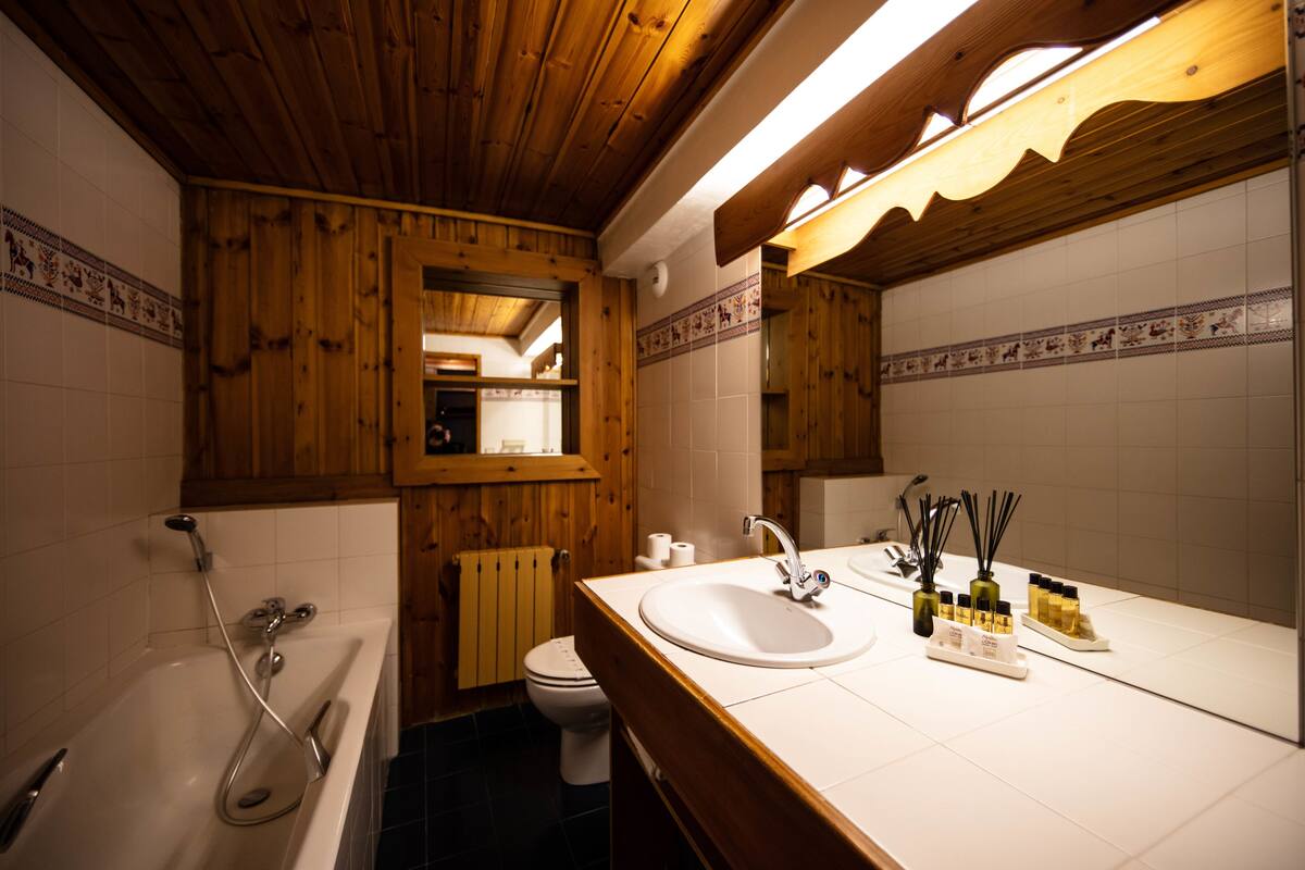 A wooden-paneled bathroom with a bathtub, toilet, and sink.