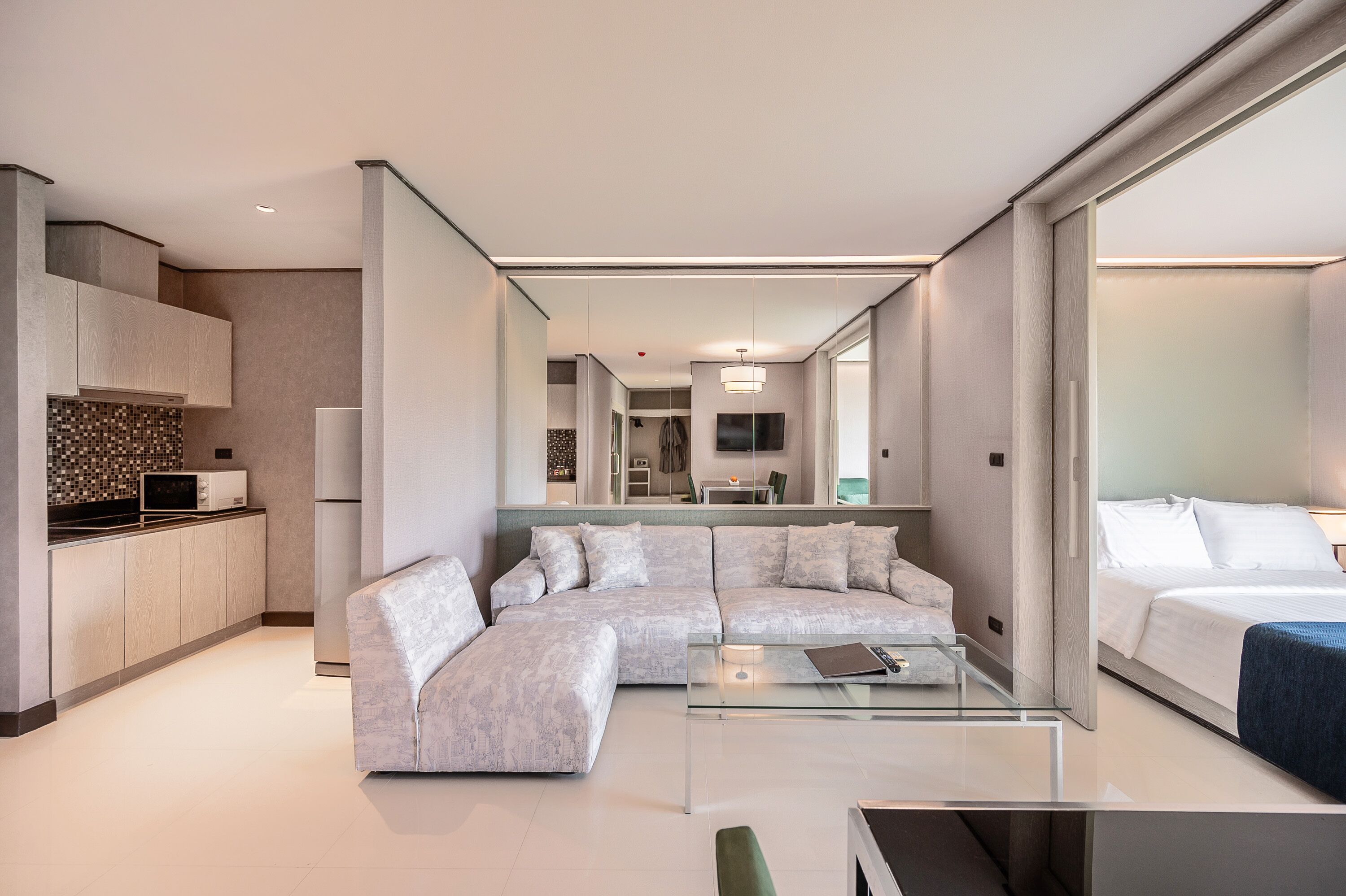Habitació d'hotel moderna amb zona de seients, petita cuina i llit.