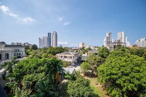 A cityscape with modern high-rise buildings and a historic building surrounded by lush greenery.