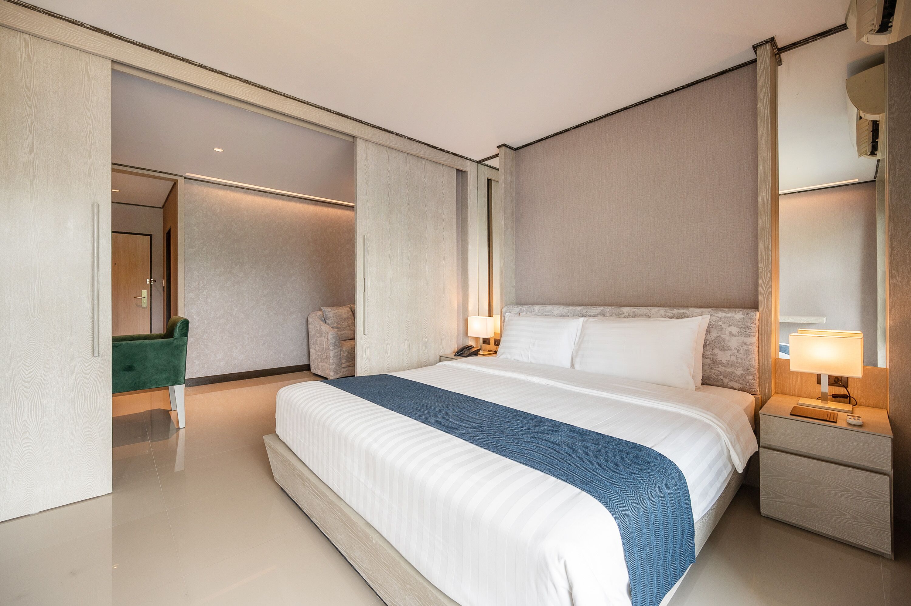 A modern hotel room with a large bed, bedside tables, a desk, and a chair.