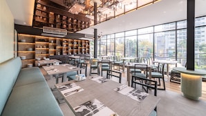A modern restaurant with high ceilings, exposed beams, and large windows offering city views. - Manhattan Pattaya Hotel (Pattaya)