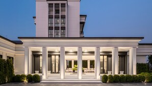 Un edificio moderno con ingresso coperto, colonne imponenti e facciata ben illuminata.