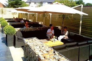 An outdoor patio area with stone seating, umbrellas, and a grill.