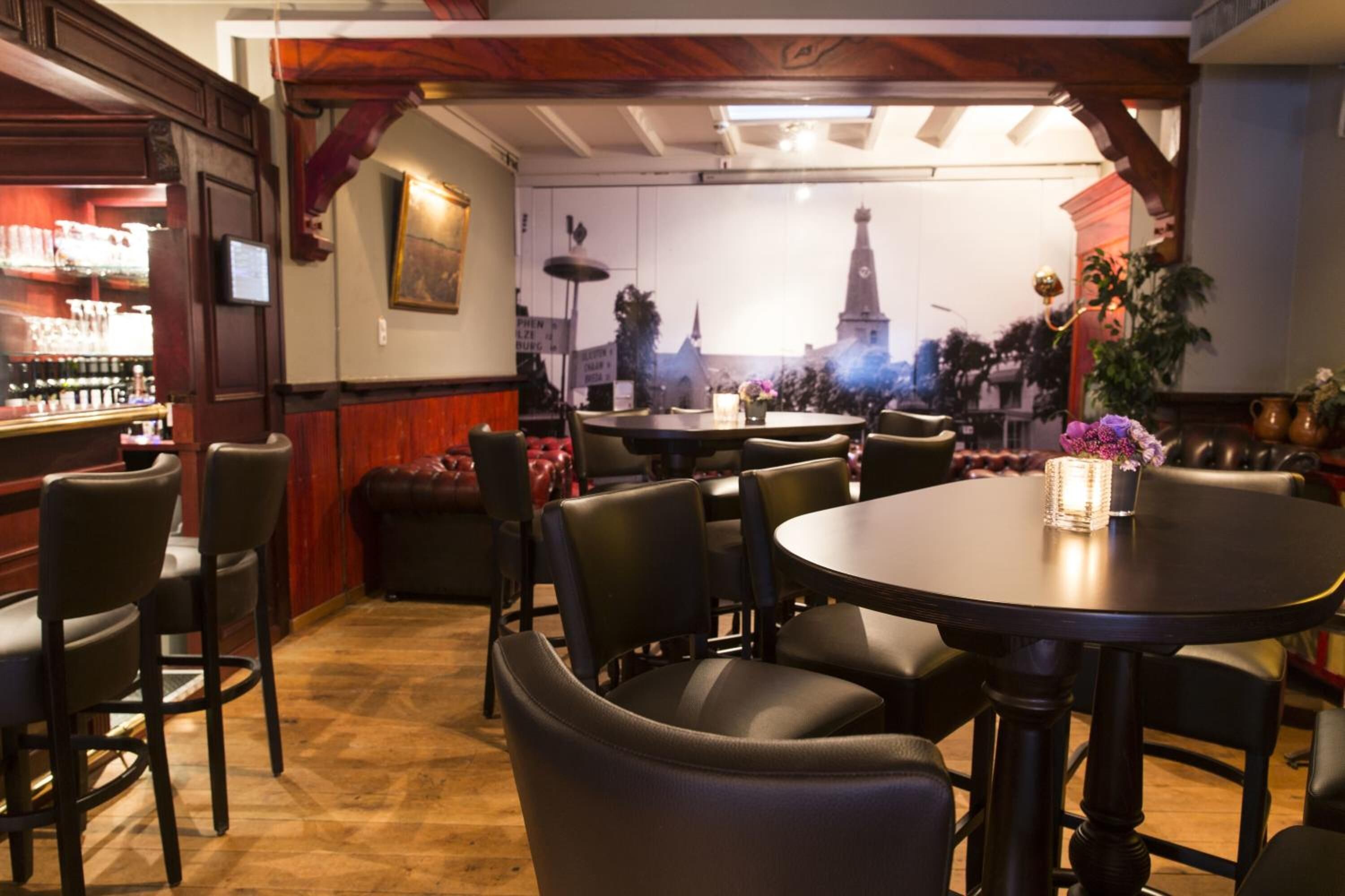Ein Restaurantinneres mit Barbereich, runden Tischen und Stühlen.