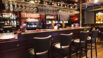 A bar area with multiple stools, a bar counter, and a variety of bottles and glasses.