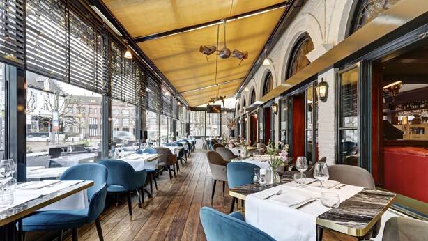 Un restaurante con suelo de madera, sillas azules y mesas dispuestas para comer.
