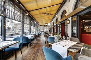 Un restaurante con suelo de madera, sillas azules y mesas dispuestas para comer.