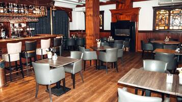A restaurant with wooden floors, bar area, and seating arrangements.