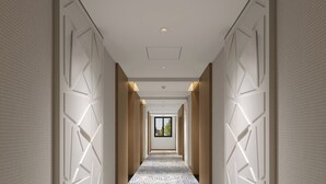 A long, narrow hallway with patterned carpet, recessed lighting, and geometric wall panels. - Holiday Inn Express Chengdu West Gate by IHG (Chengdu)
