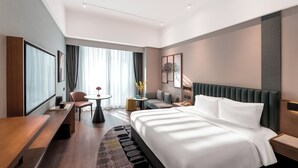 A modern hotel room with a large bed, a desk, a chair, and a small table with a vase of flowers. - Holiday Inn Express Chengdu West Gate by IHG (Chengdu)