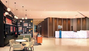 A modern hotel lobby with a reception desk, seating area, and a bookshelf filled with books and framed pictures. - Holiday Inn Express Chengdu West Gate by IHG (Chengdu)