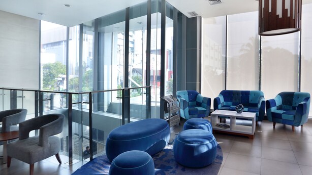 Un salon moderne avec des murs en verre, des meubles bleus et une vue sur la ville.