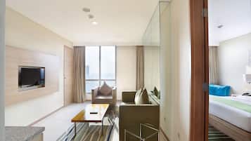 Habitación de hotel moderna con televisión de pantalla plana, un sofá, una cama, una mesita y vistas a la ciudad.