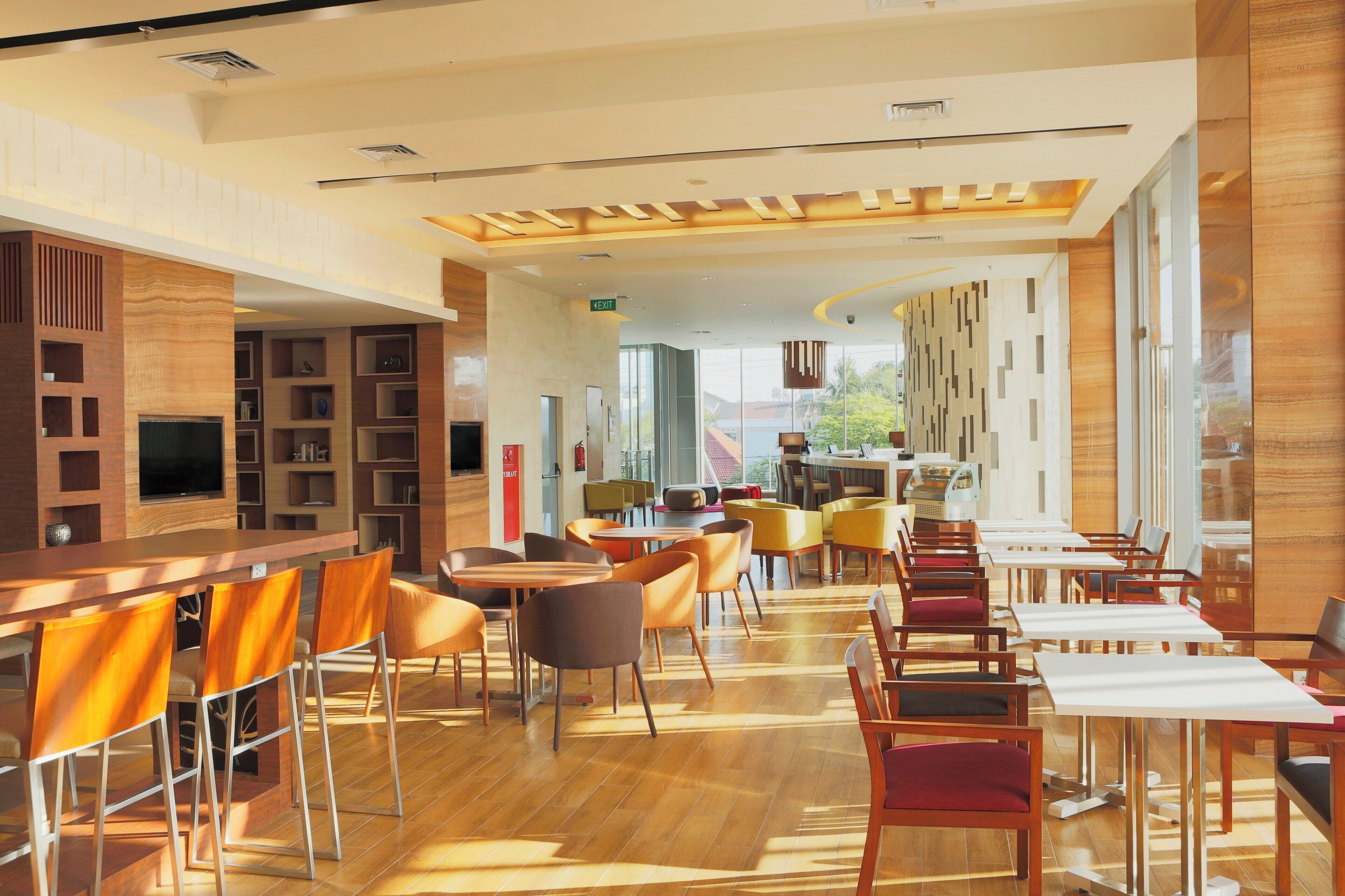 A modern restaurant interior with wooden flooring, multiple seating areas, and a bar counter.