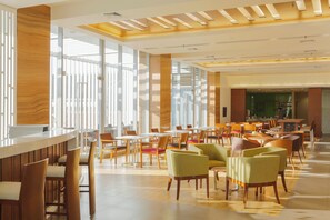 A spacious indoor area with multiple seating arrangements, large windows, and a kitchen area. - Holiday Inn Express Semarang Simpang Lima by IHG (Semarang)
