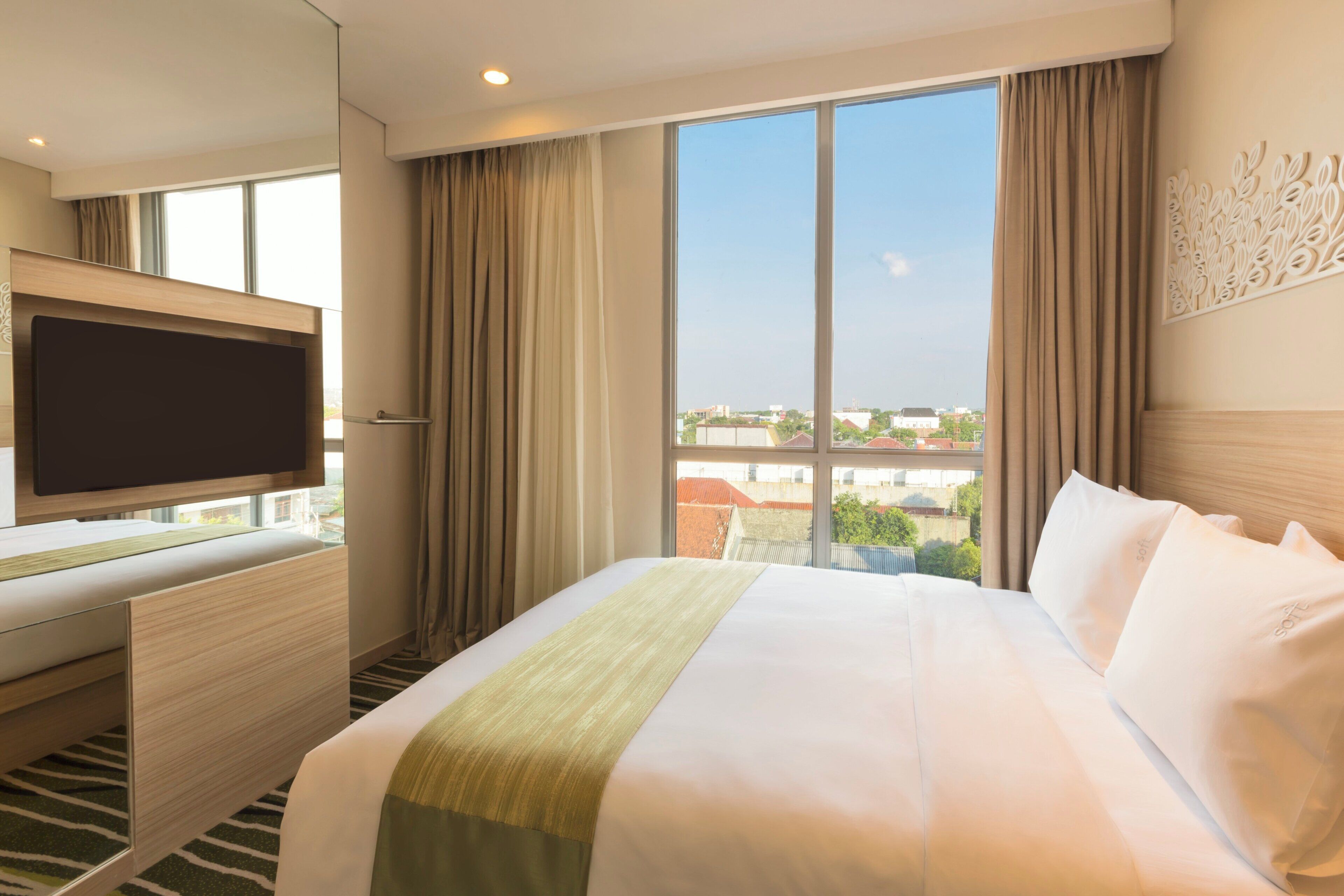 Une chambre d’hôtel avec un grand lit, une télévision à écran plat et une vue sur la ville.
