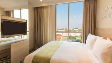Une chambre d’hôtel avec un grand lit, une télévision à écran plat et une vue sur la ville.