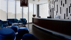 Un hall d’entrée moderne avec des sièges bleus, un comptoir d’accueil et de grandes fenêtres.