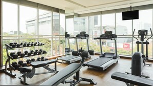 Une salle de sport équipée de tapis de course, d’haltères et d’un banc de musculation.