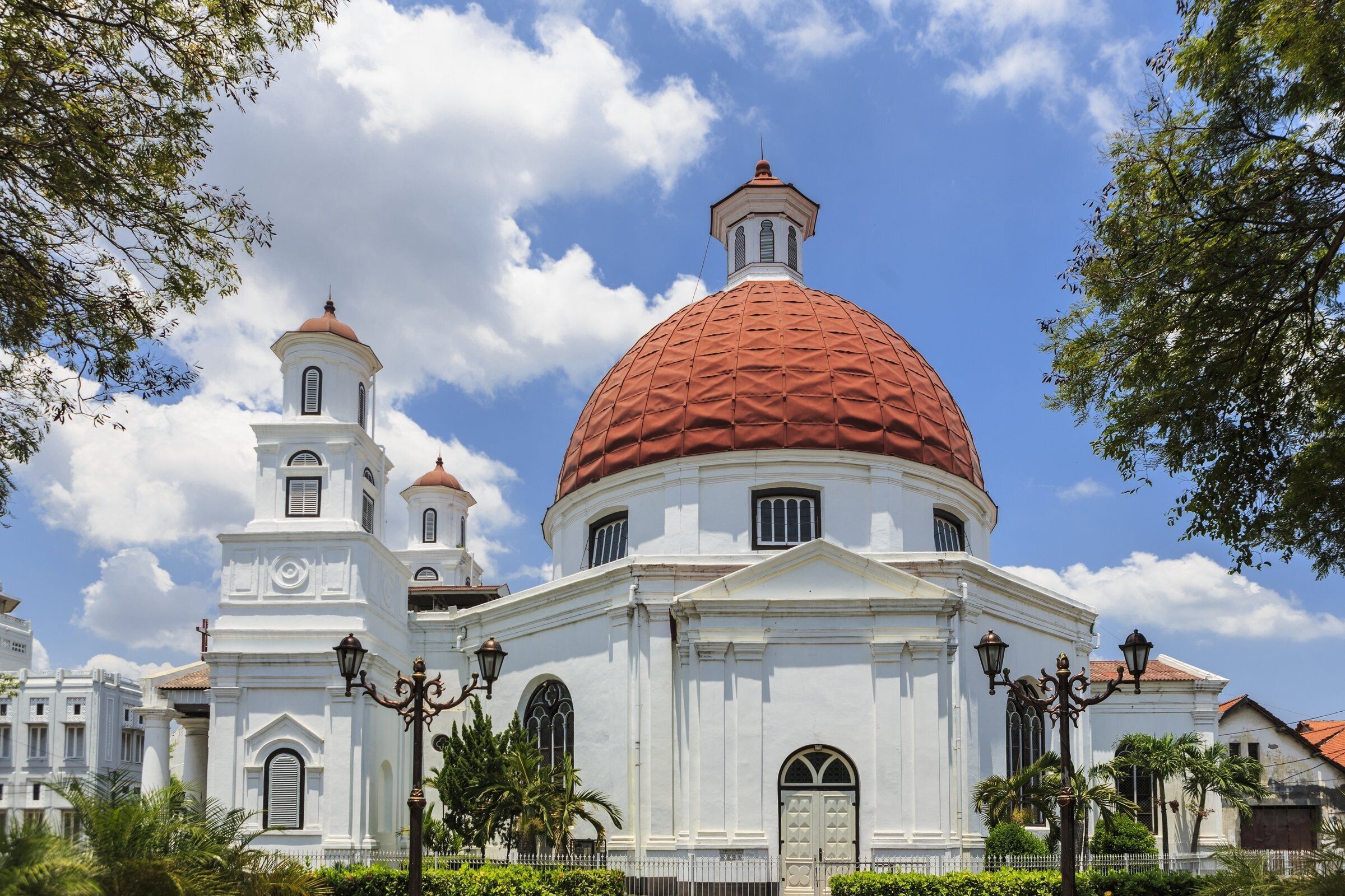 A white church with a large red dome and smaller domes on the side.