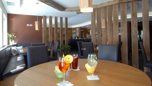 Ein Restaurant mit einem runden Holztisch, zwei Getränken und einer Sitzecke mit einer Couch und Stühlen.