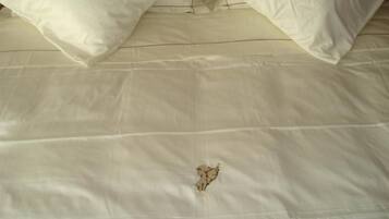 Un letto con biancheria bianca e un ricamo decorativo a forma di angelo.
