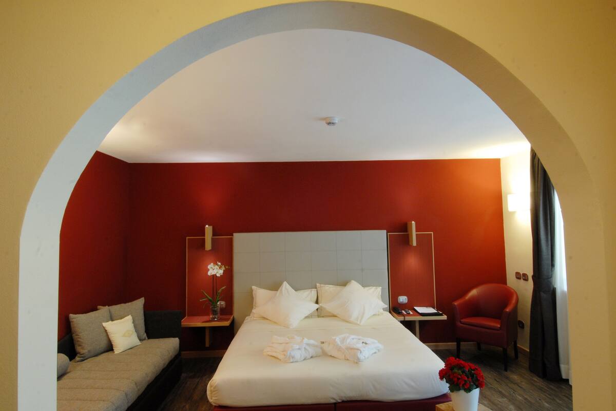 Une chambre d’hôtel avec un grand lit, un canapé, un fauteuil et un bureau.