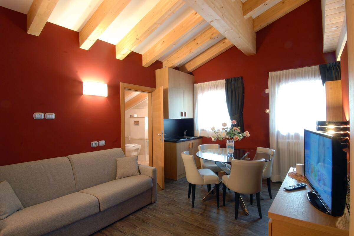 Un salon confortable avec un canapé, une table à manger, des chaises et un téléviseur.