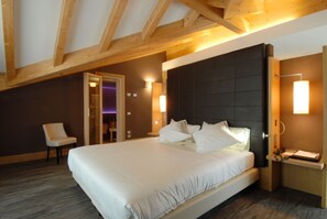 Een hotelkamer met een groot bed, houten balken in het plafond en een nachtkastje met een lamp.