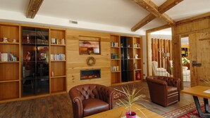 Ein gemütliches Wohnzimmer mit Holzbücherregalen, Ledersesseln und einem Kamin.