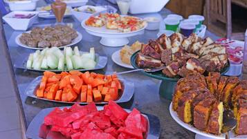 Una mesa de buffet con diversos platos, incluyendo sandía en rodajas, zanahorias, y una variedad de carnes y quesos.