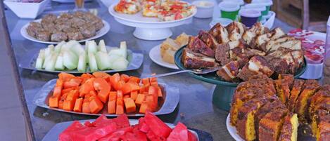 A buffet table with various dishes including sliced watermelon, carrots, and a variety of meats and cheeses.