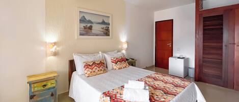 A neatly arranged bedroom with a bed, bedside tables, a painting, a wardrobe, and a small desk with a chair.