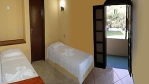 Un alojamiento pequeño y de una sola habitación, con cama, puerta y ventana.