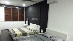 A bedroom with a large bed, a smaller bed, a nightstand, a lamp, and a wall-mounted air conditioner. - Kimberley House (George Town)