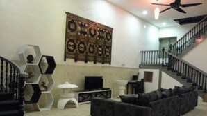 A living room with a sofa, a TV, and a staircase. - Kimberley House (George Town)