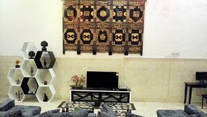 A living room with a sofa set, a coffee table, a TV on a stand, and a decorative wall panel. - Kimberley House (George Town)