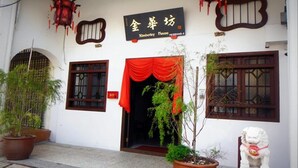 A traditional building with a sign reading "Kimberley House." There are two potted plants in front, a red curtain over the entrance, and a white lion statue to the right. - Kimberley House (George Town)