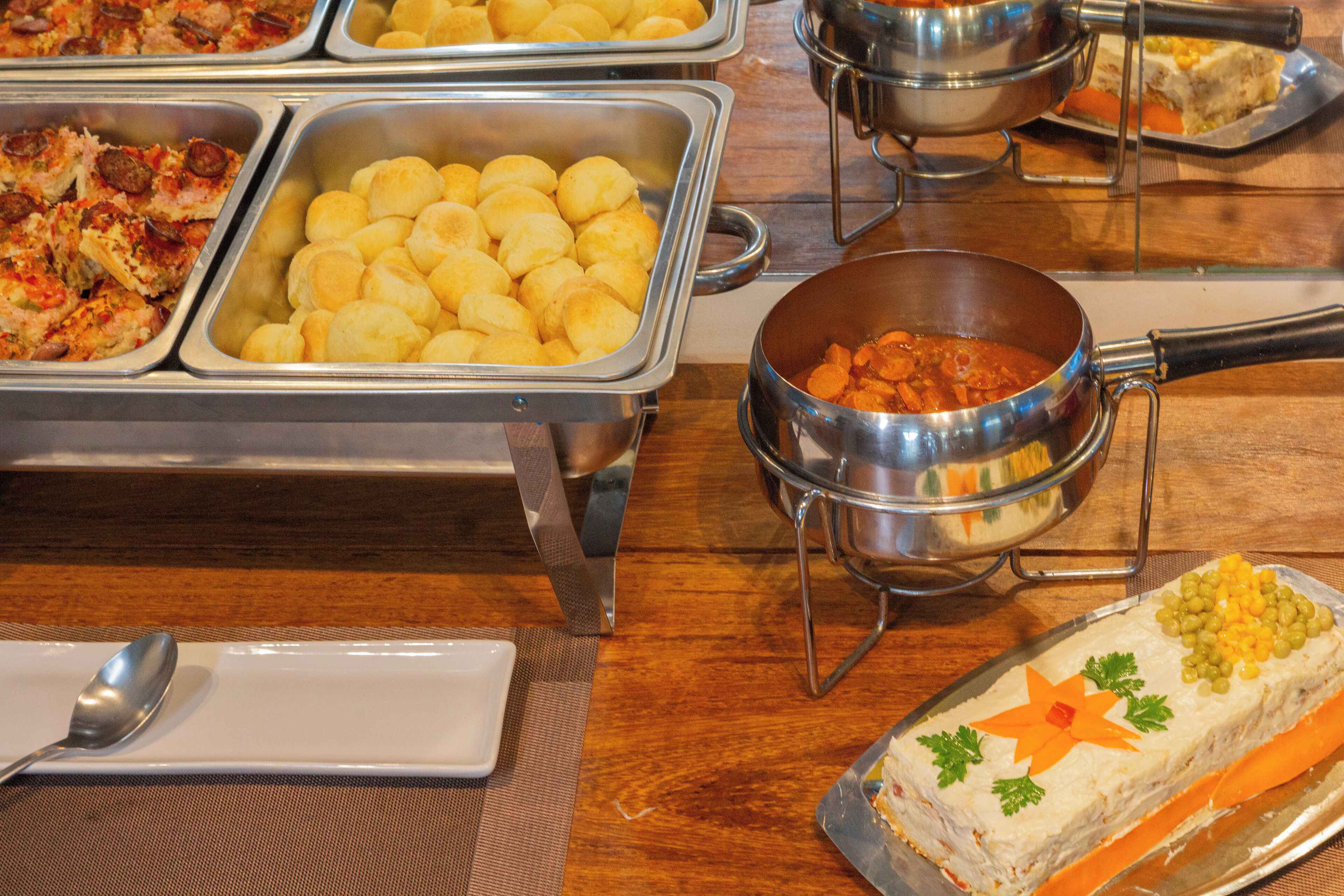 A buffet with various food items including bread, a dish with corn, and a decorated cake.