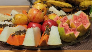 Una bandeja de frutas con manzanas, plátanos y papaya.