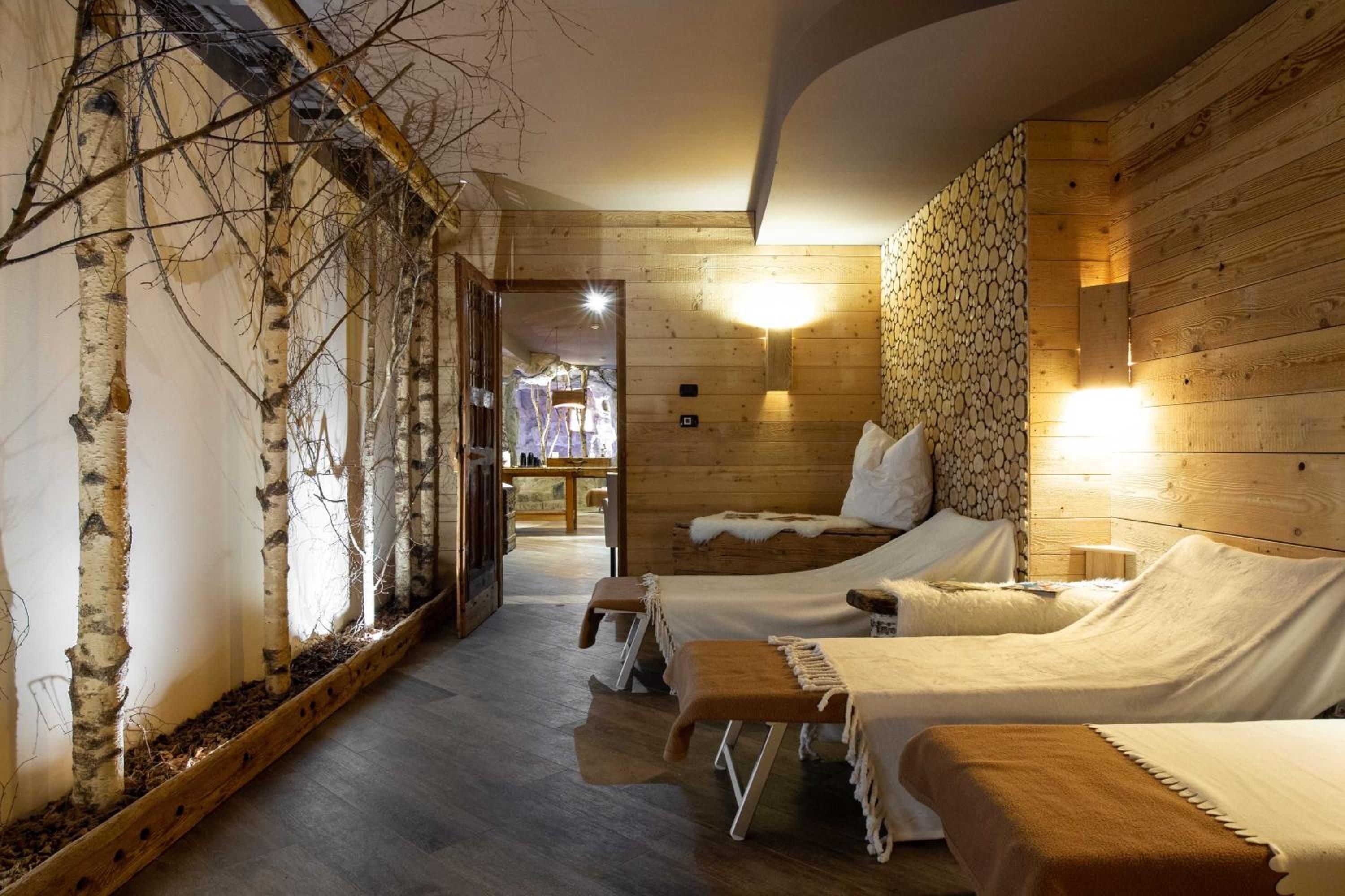 A wooden interior with two beds, a bench, and a wall-mounted light fixture.