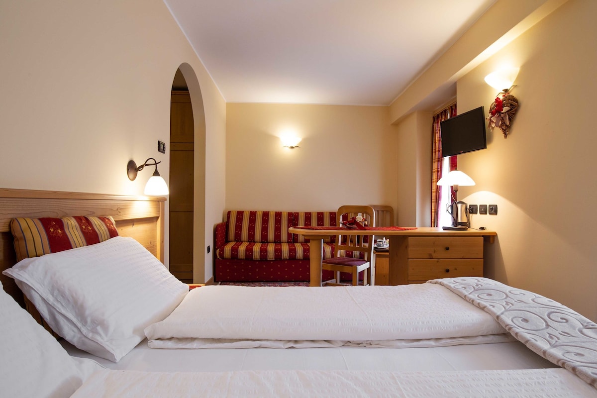 Ein Hotelzimmer mit einem Bett, einem Schlafsofa, einem Schreibtisch und einem Fernseher.