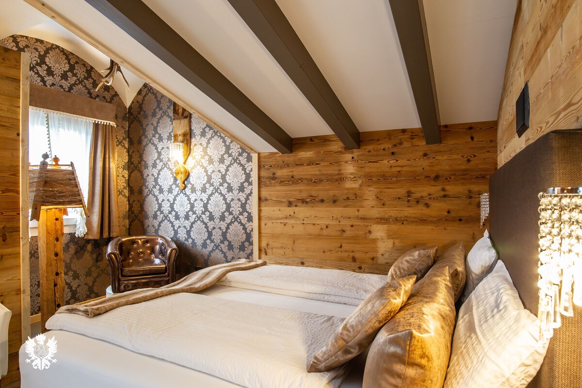 Ein Zimmer mit Holzwänden, einem Bett, einem Sessel und einer Wandleuchte.